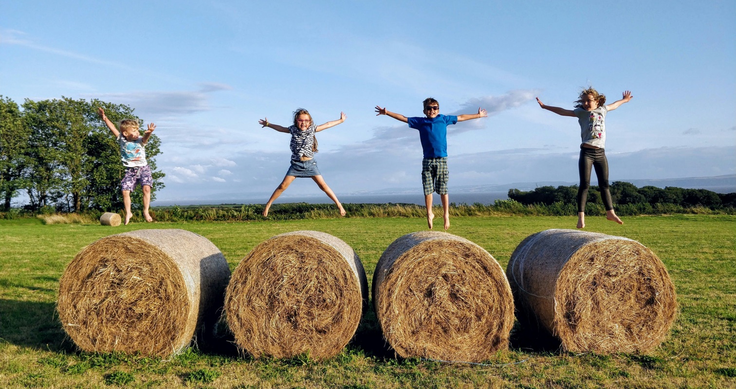 kids jumping on large bales of hay